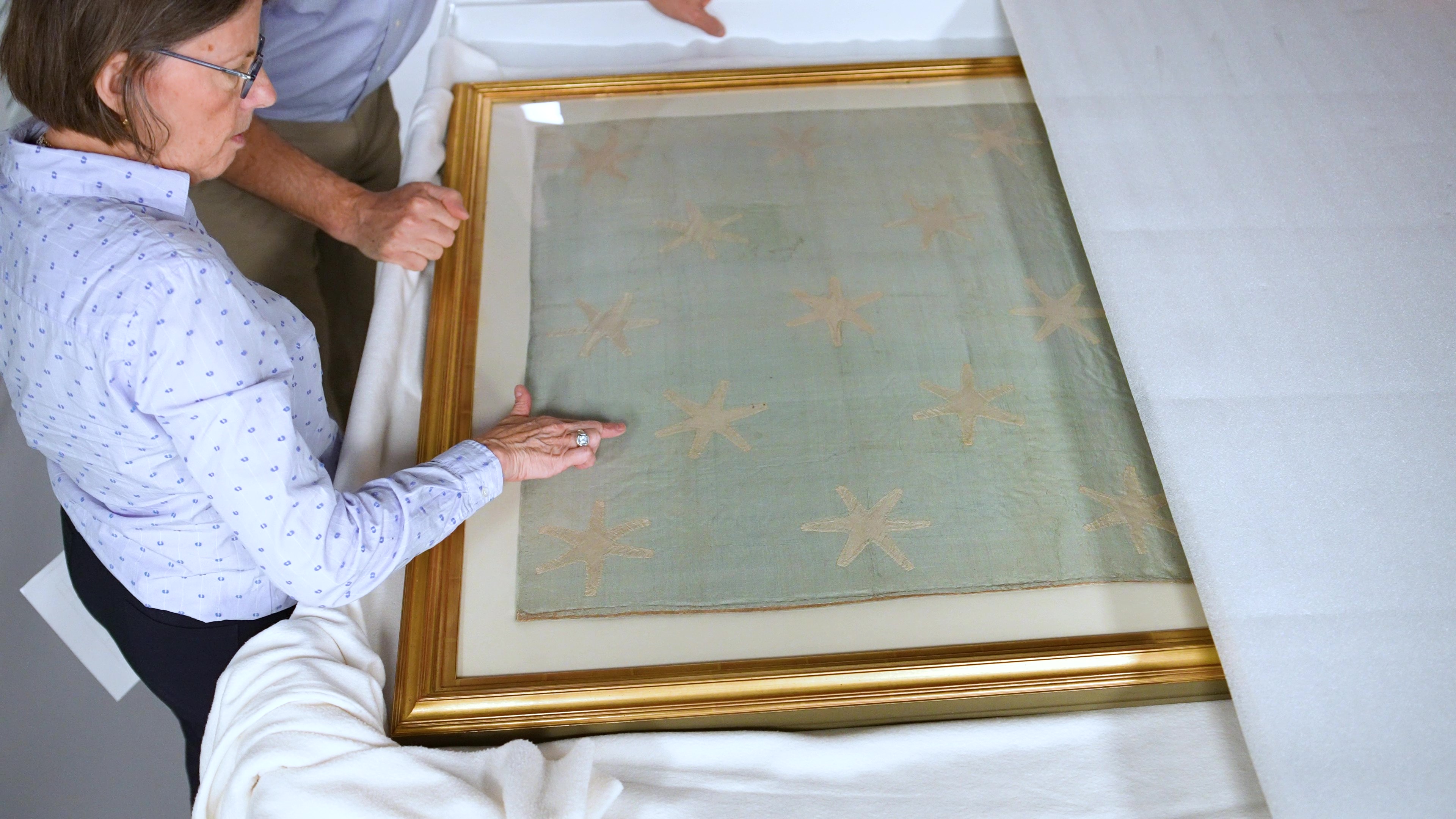 Textile conservator Virginia Whelan views the Washington Standard flag in the Museum's collection workroom.