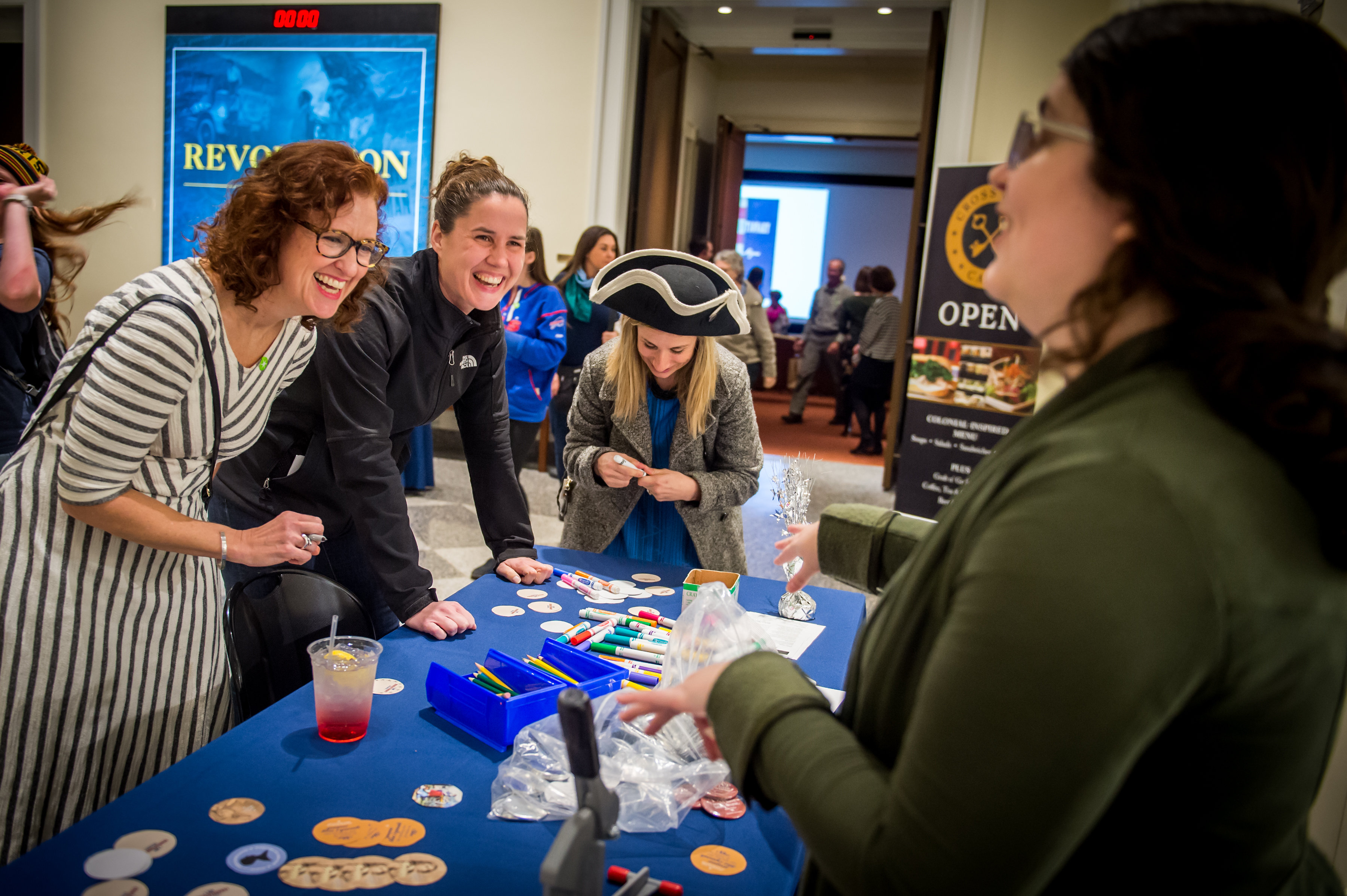 Women laughing and interacting with Museum staff at a History After Hours event in the Museum lobby.