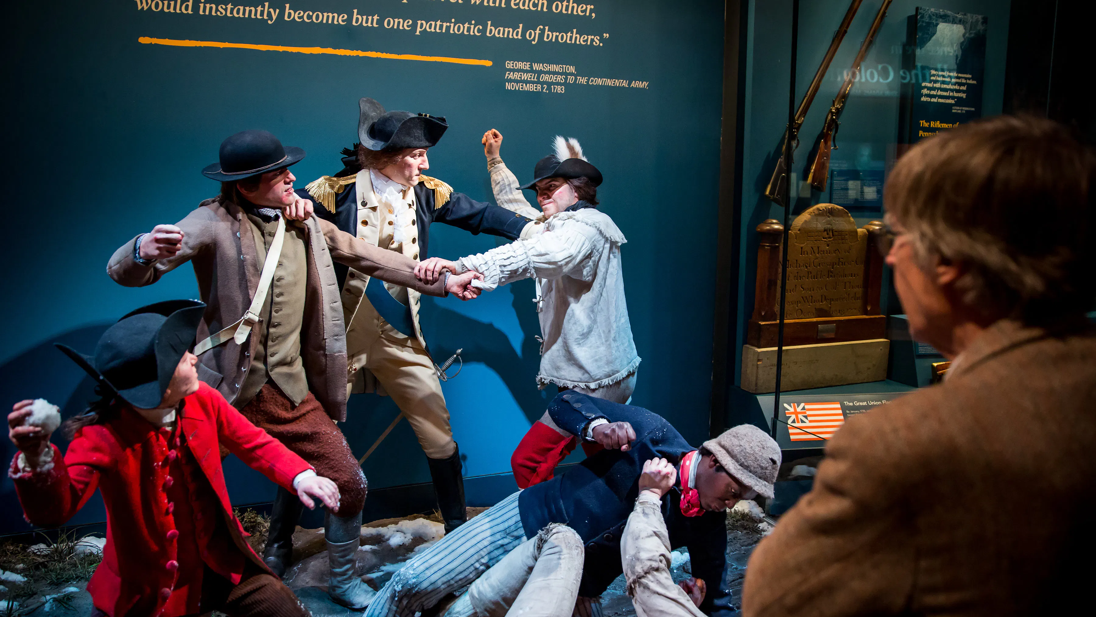 A visitor looks at a tableau scene depicting George Washington breaking up a fight among his troops in Harvard Yard.