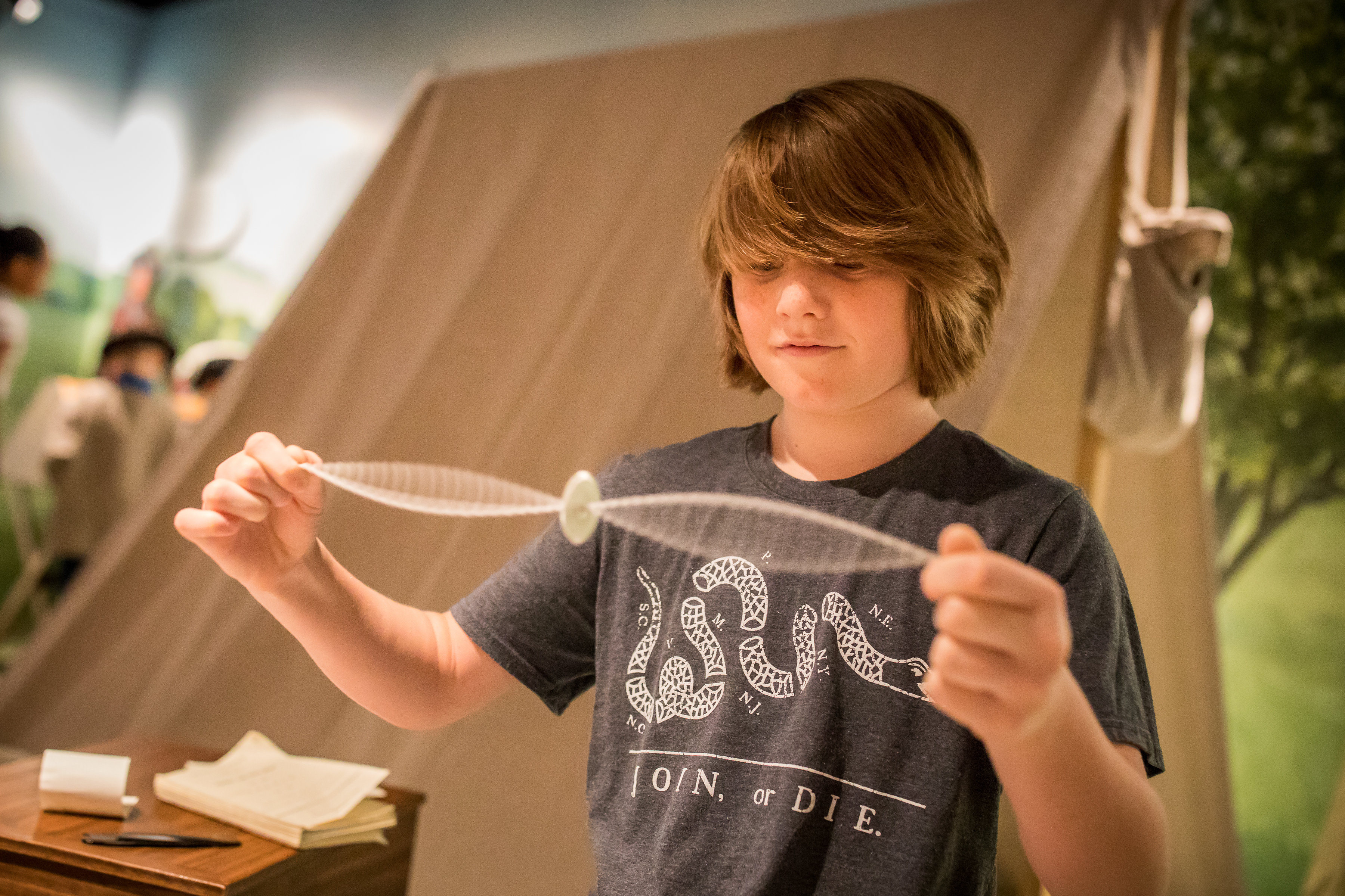 A white adolescent male plays with a Revolutionary-style whirligig.