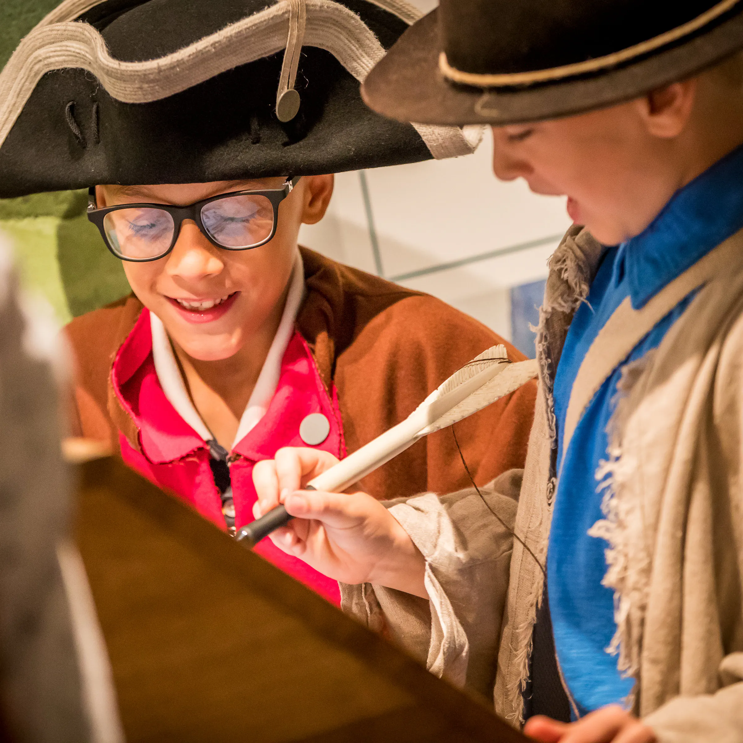 This image shows two adolescent males, in military costume, enjoying a digital feature in Revolution Place.