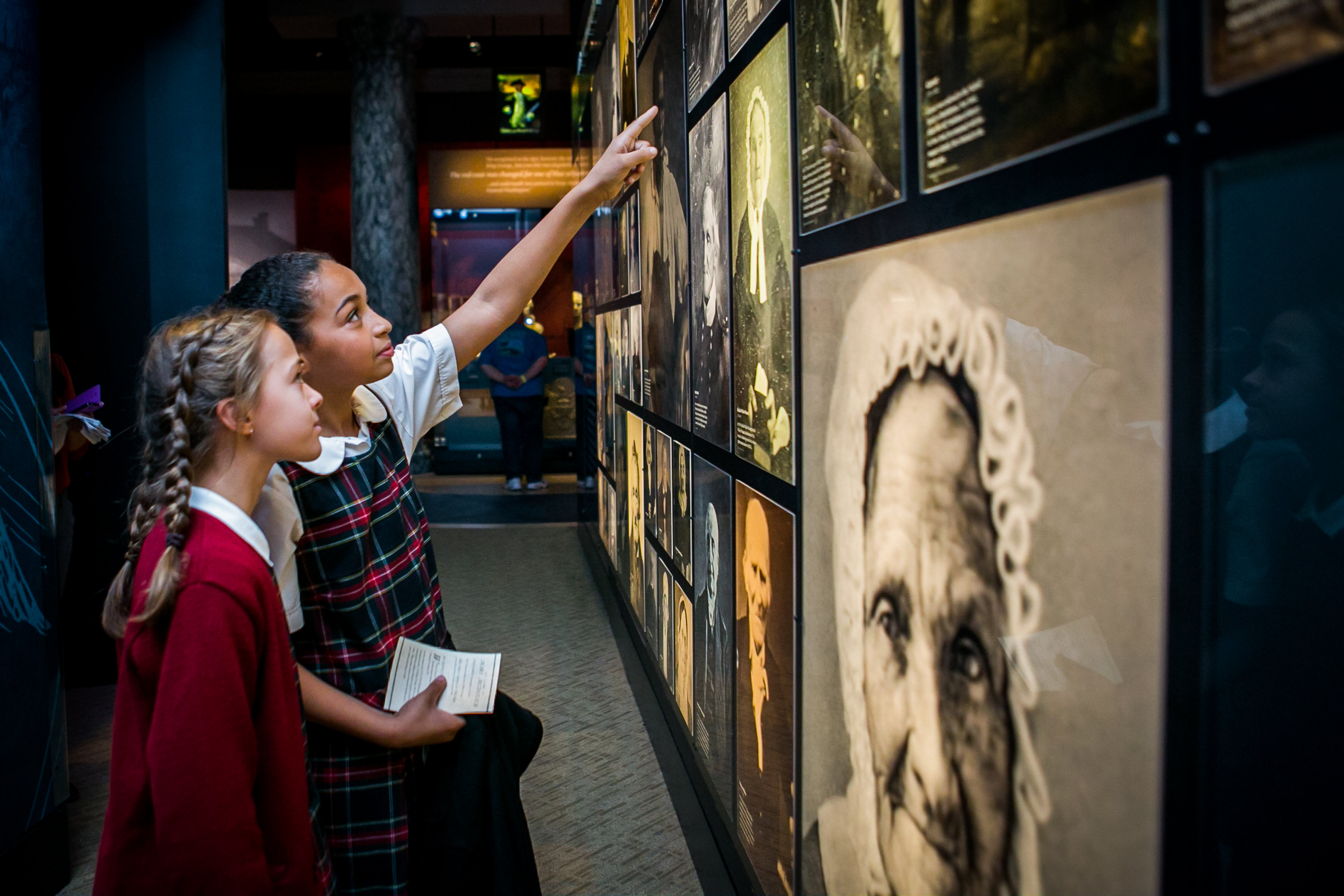 Schoolchildren reading and pointing at an exhibit during a field trip.