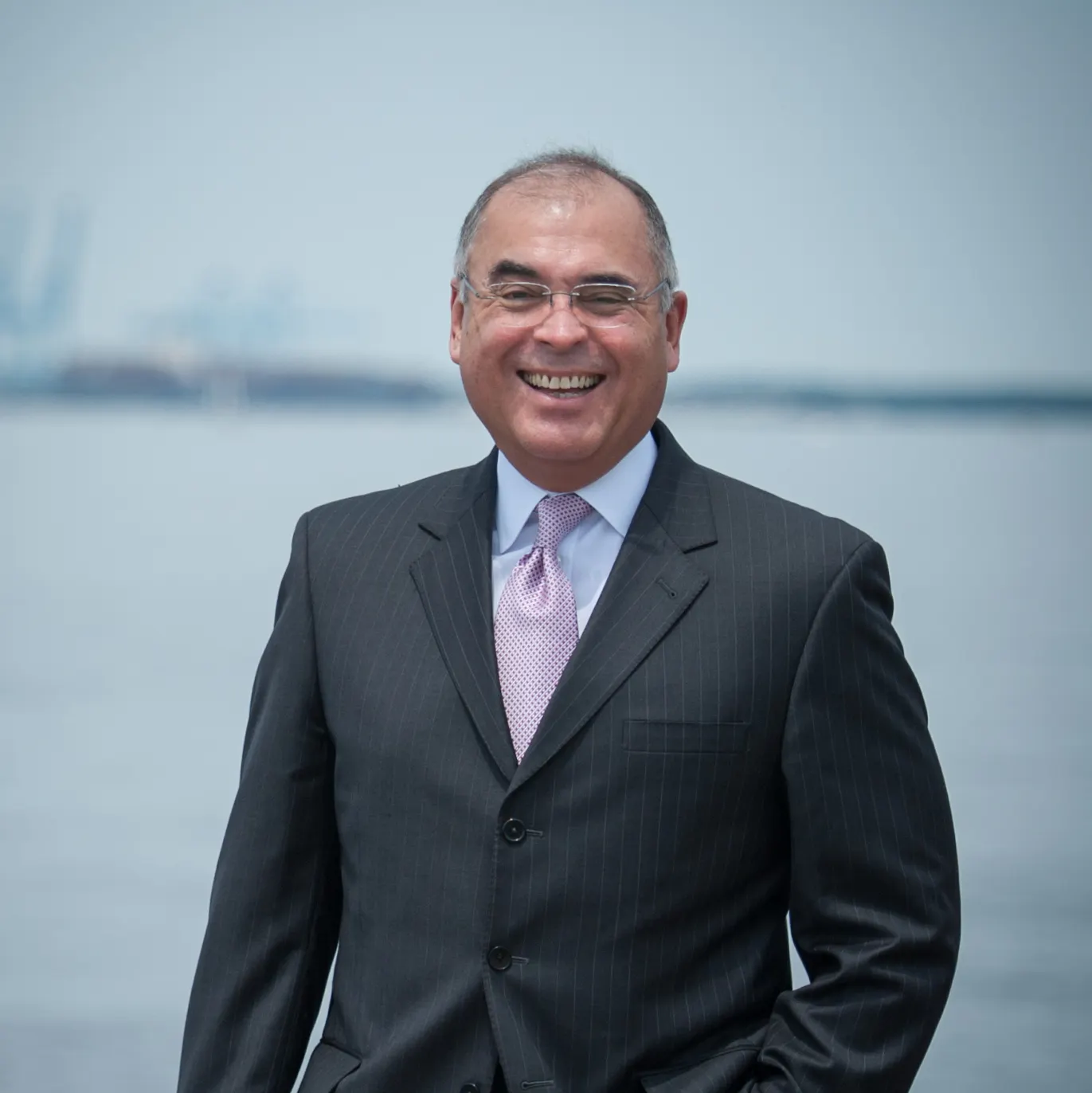 Ricardo Herrera headshot wearing a black suit with a blue shit and purple tie.