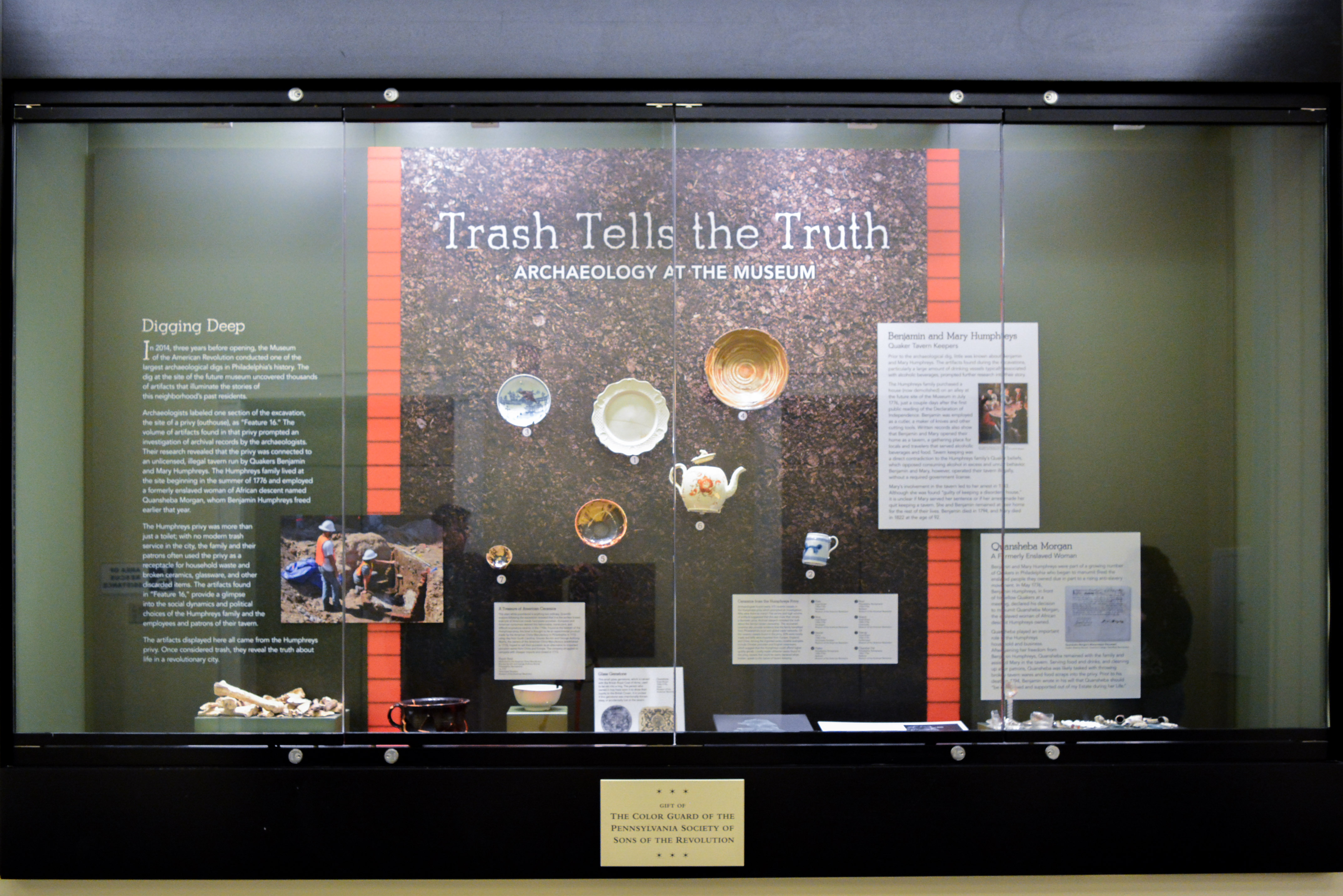 This image shows a display case featuring artifacts found in a privy pit during a dig at the site of the Museum.