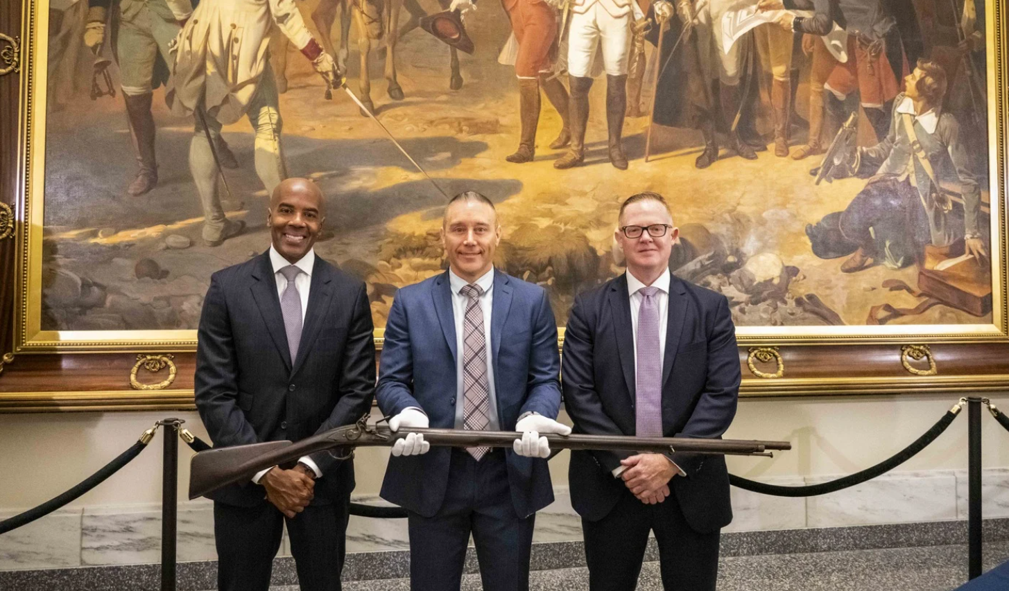 From left to right, FBI Philadelphia Special Agent in Charge Wayne A. Jacobs, Special Agent Jake Archer of the FBI Art Crime Team, and Assistant Special Agent in Charge Jamie Milligan pose with a Revolutionary War-era musket that was returned to the Museum of the American Revolution in Philadelphia on July 1, 2024.