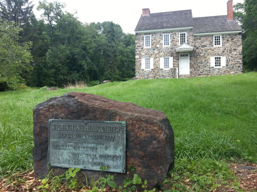 This image shows a plaque on a rock memorializing the site of the house that served as Washington's headquarters at the Battle of Brandywine.