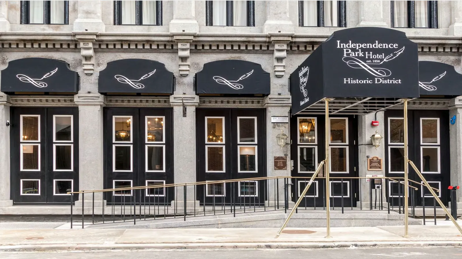 This image shows the white-gray facade with black details of the Independence Park Hotel across the street from the Museum.