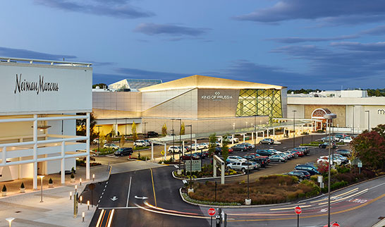 An exterior view of the King of Prussia Mall with it's glowing glass and white structure.