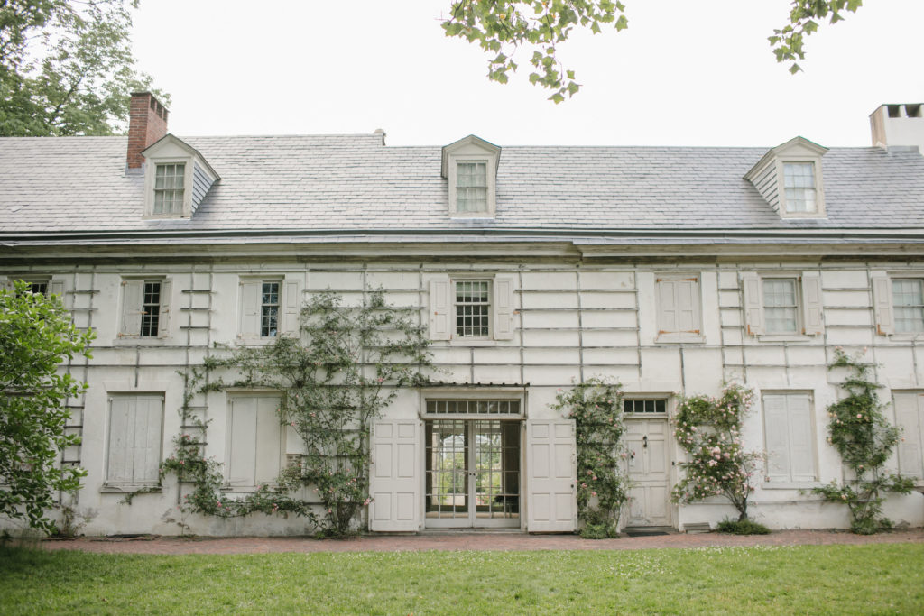 This image shows the Wyck House with white paneling and green plants growing up the facade.