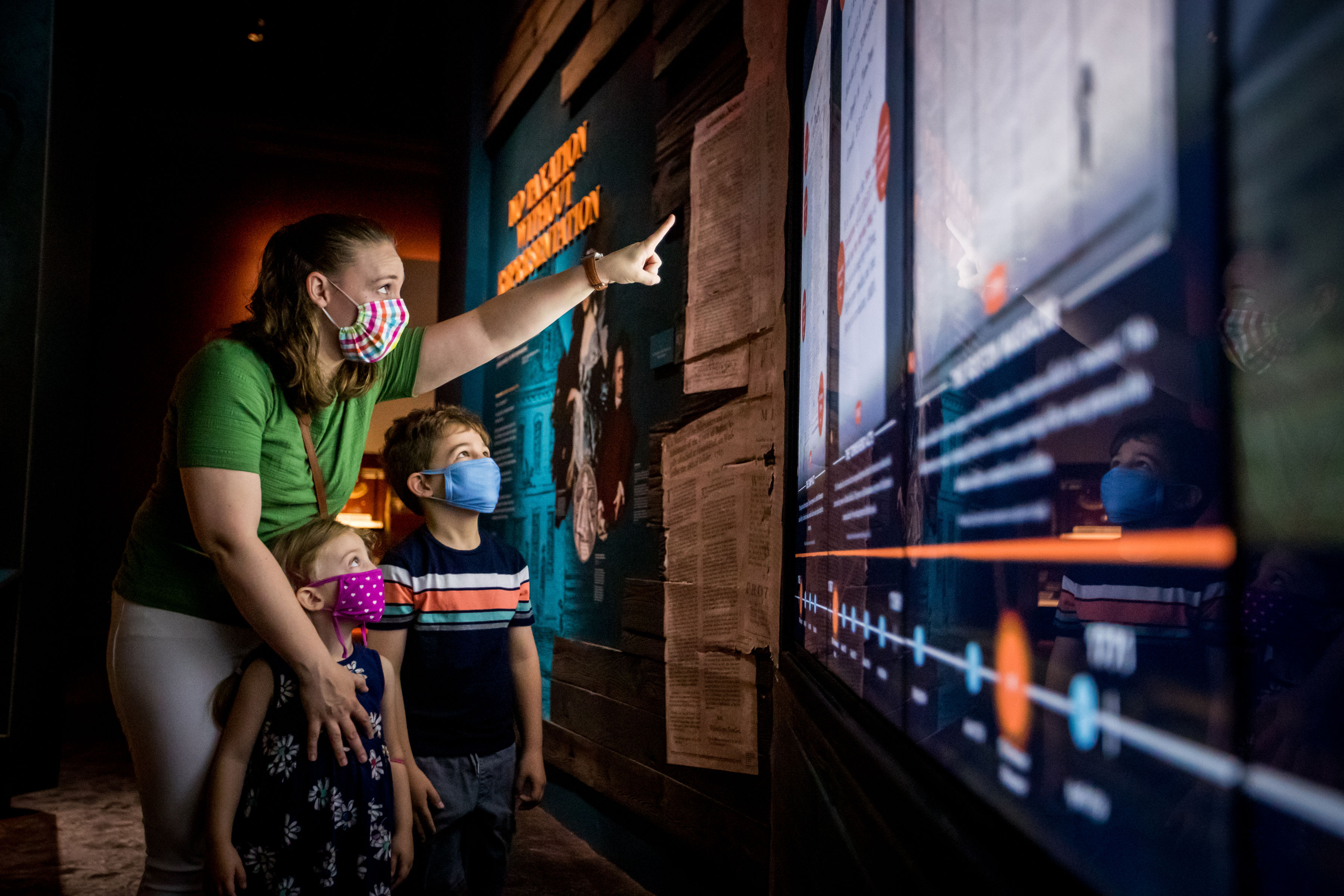 A mother and her two children, wearing masks, explore the galleries.