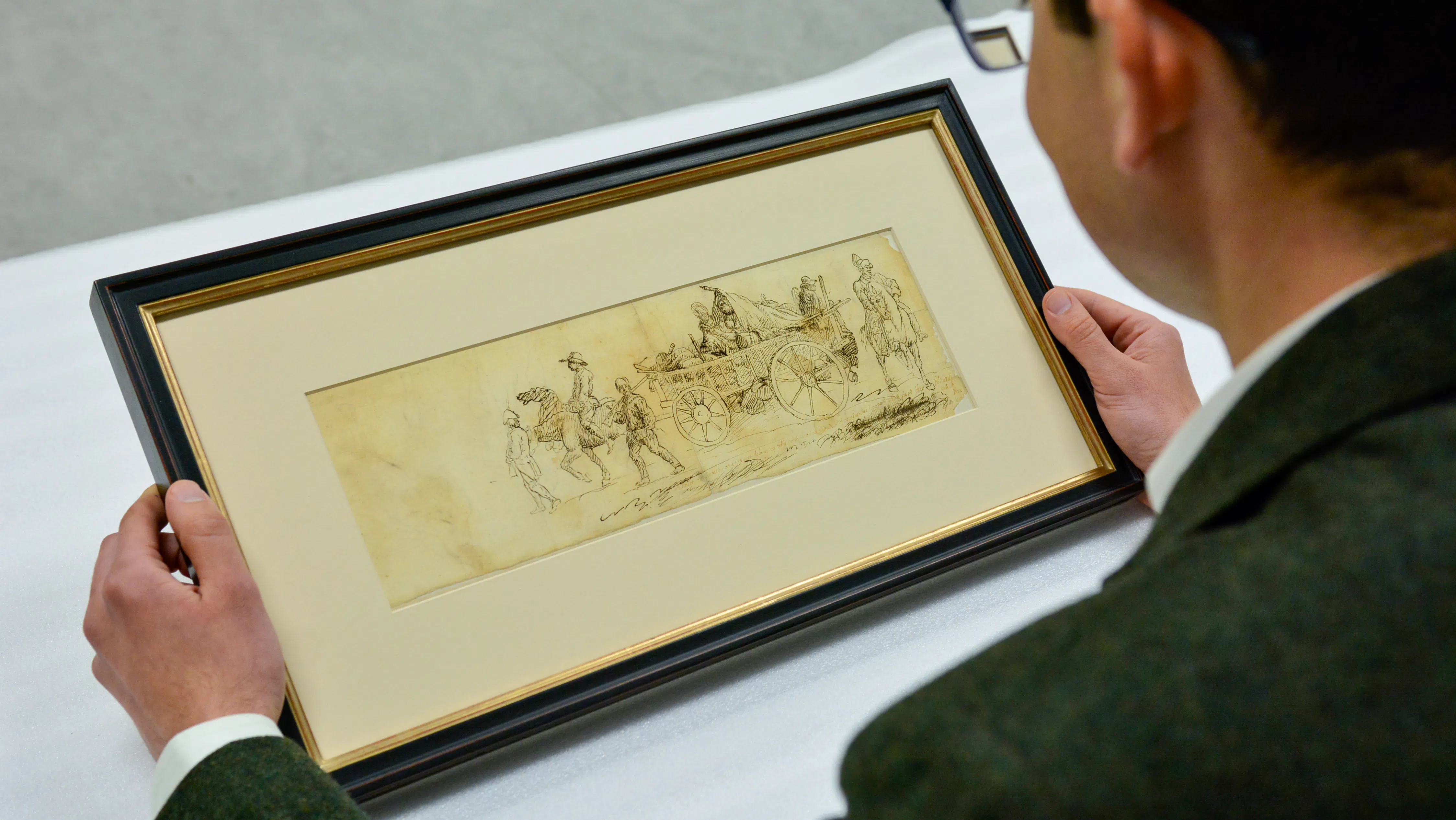 Curator Matthew Skic holds and views the framed eyewitness sketch of the North Carolina Brigade and women camp followers marching through Philadelphia.
