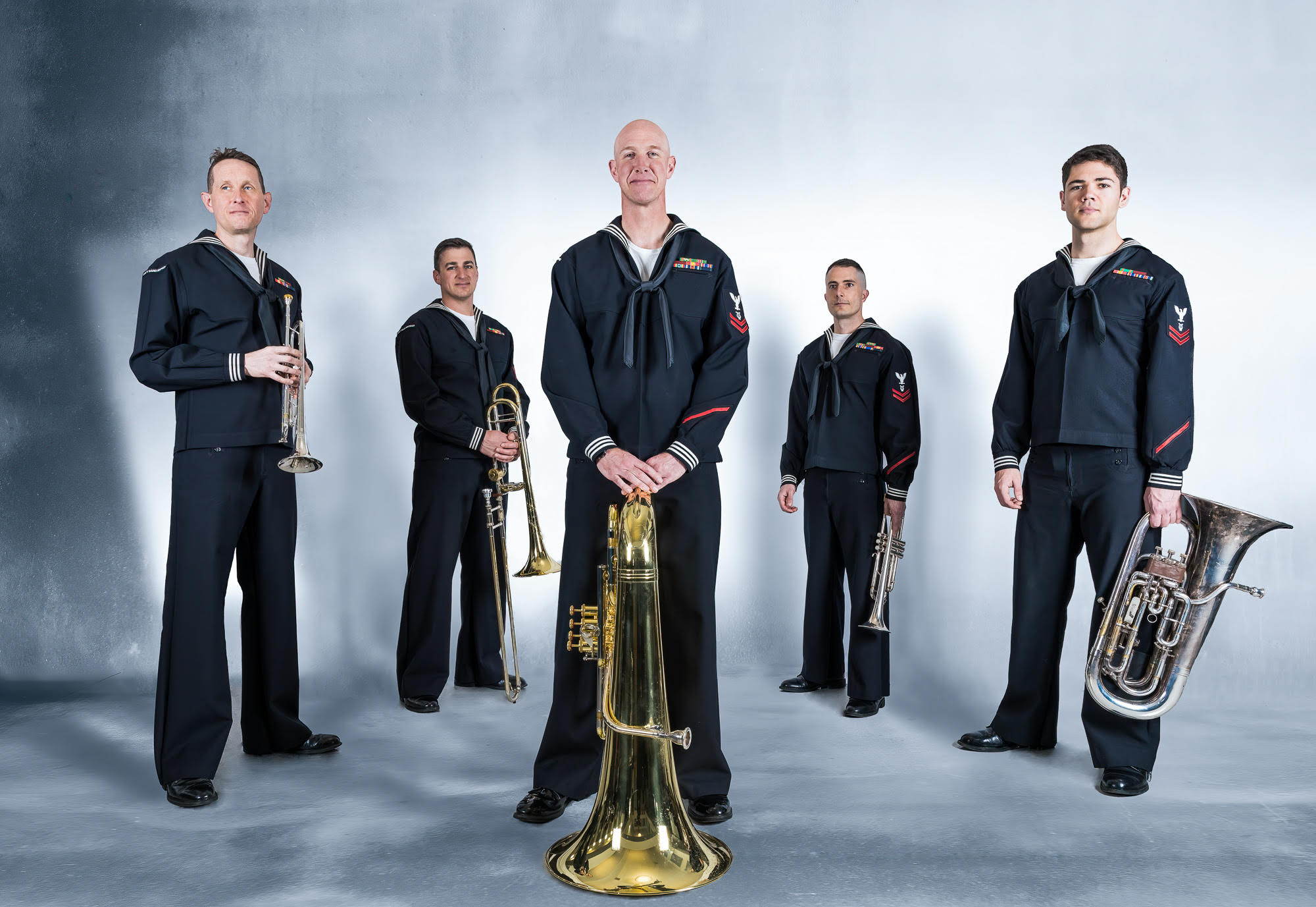 Members of the US Navy Band Northeast quintet holding their instruments while dressed in uniform.