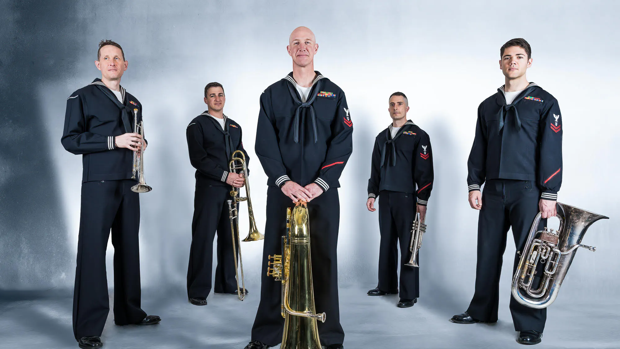 Members of the US Navy Band Northeast quintet holding their instruments while dressed in uniform.