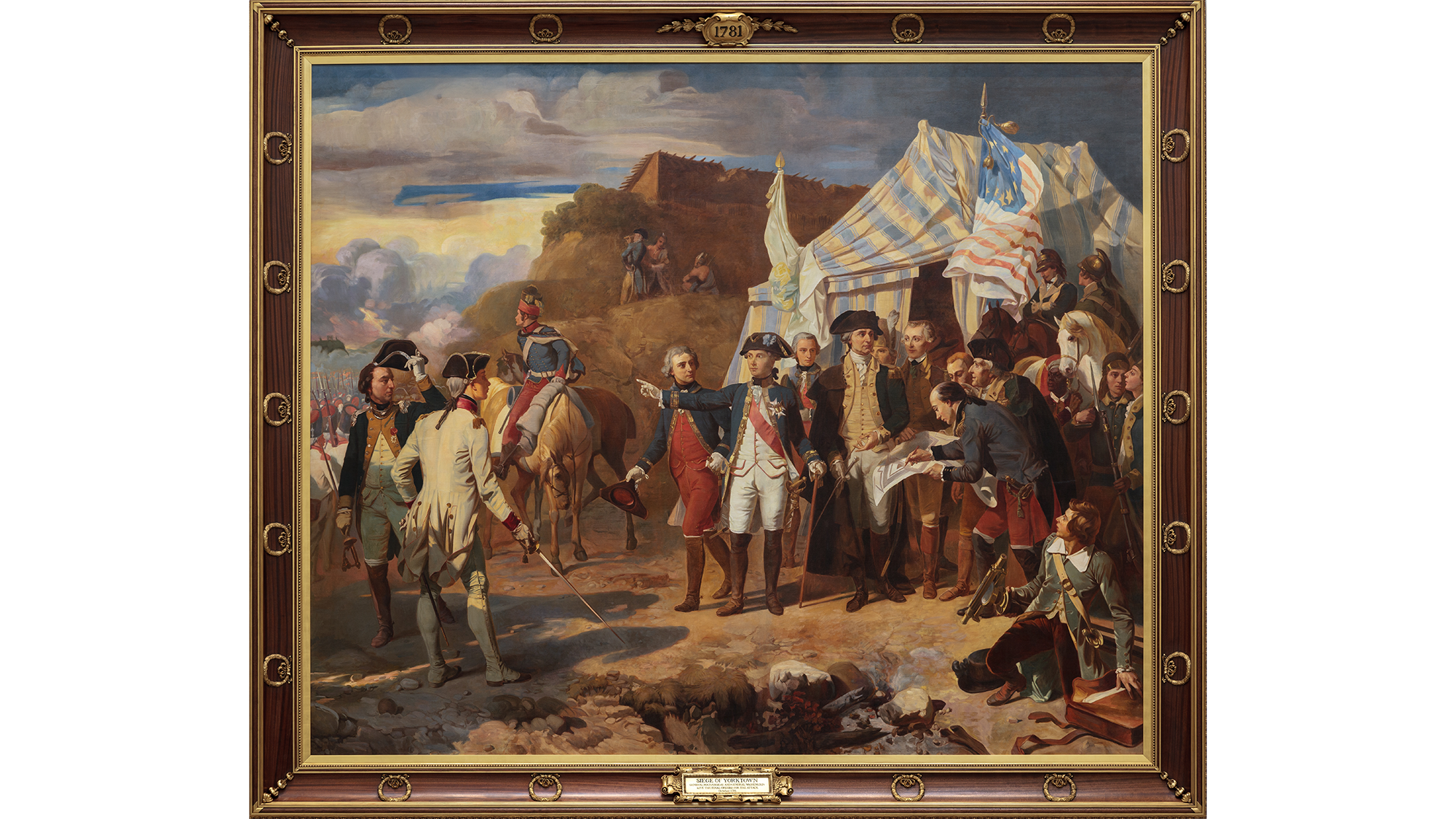 This image shows The Siege of Yorktown painting. The frame is brown with circular gold symbols. It says “1781” at the top of the frame.