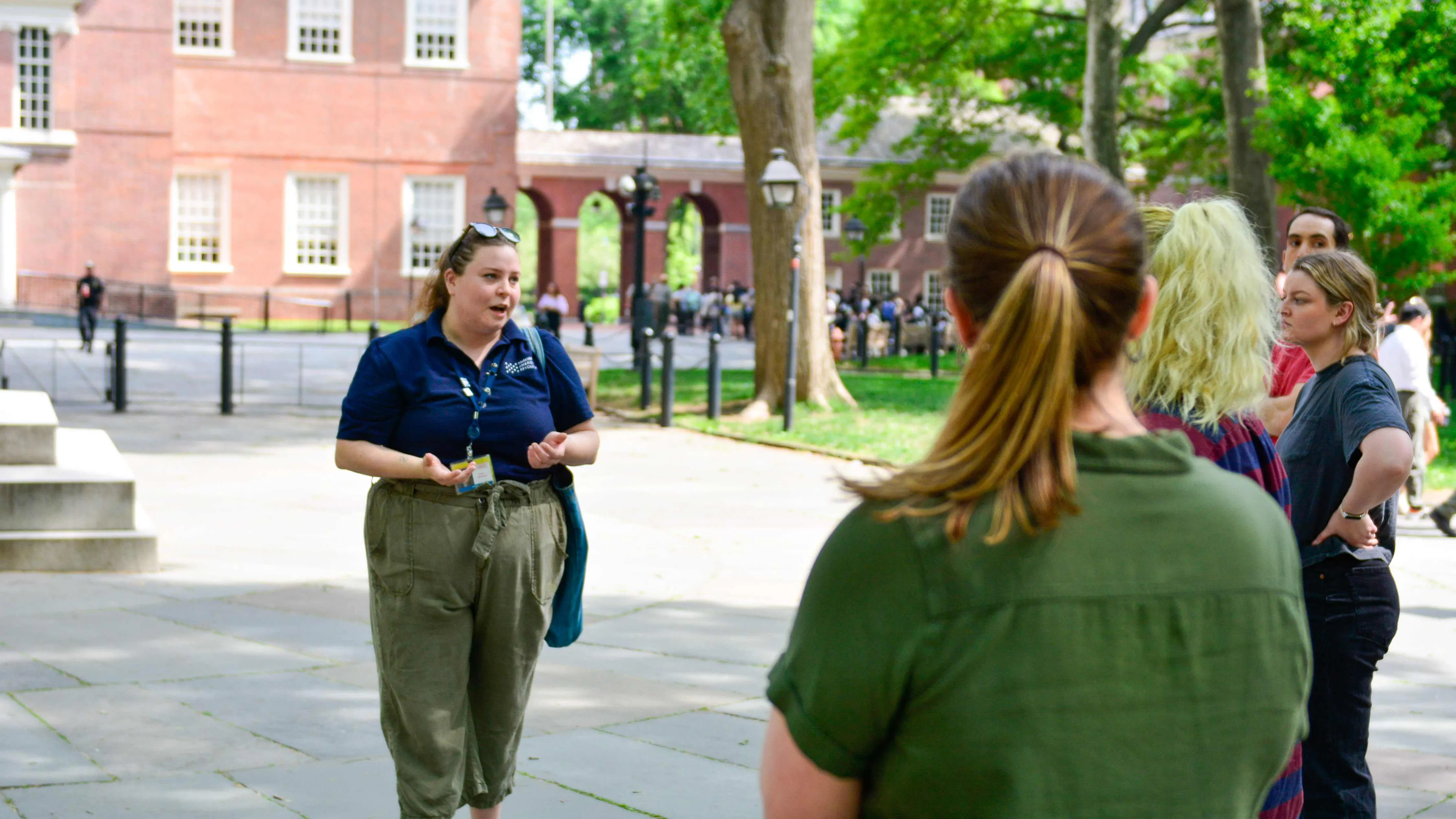 A Museum educator talks to people in front of Independence Hall