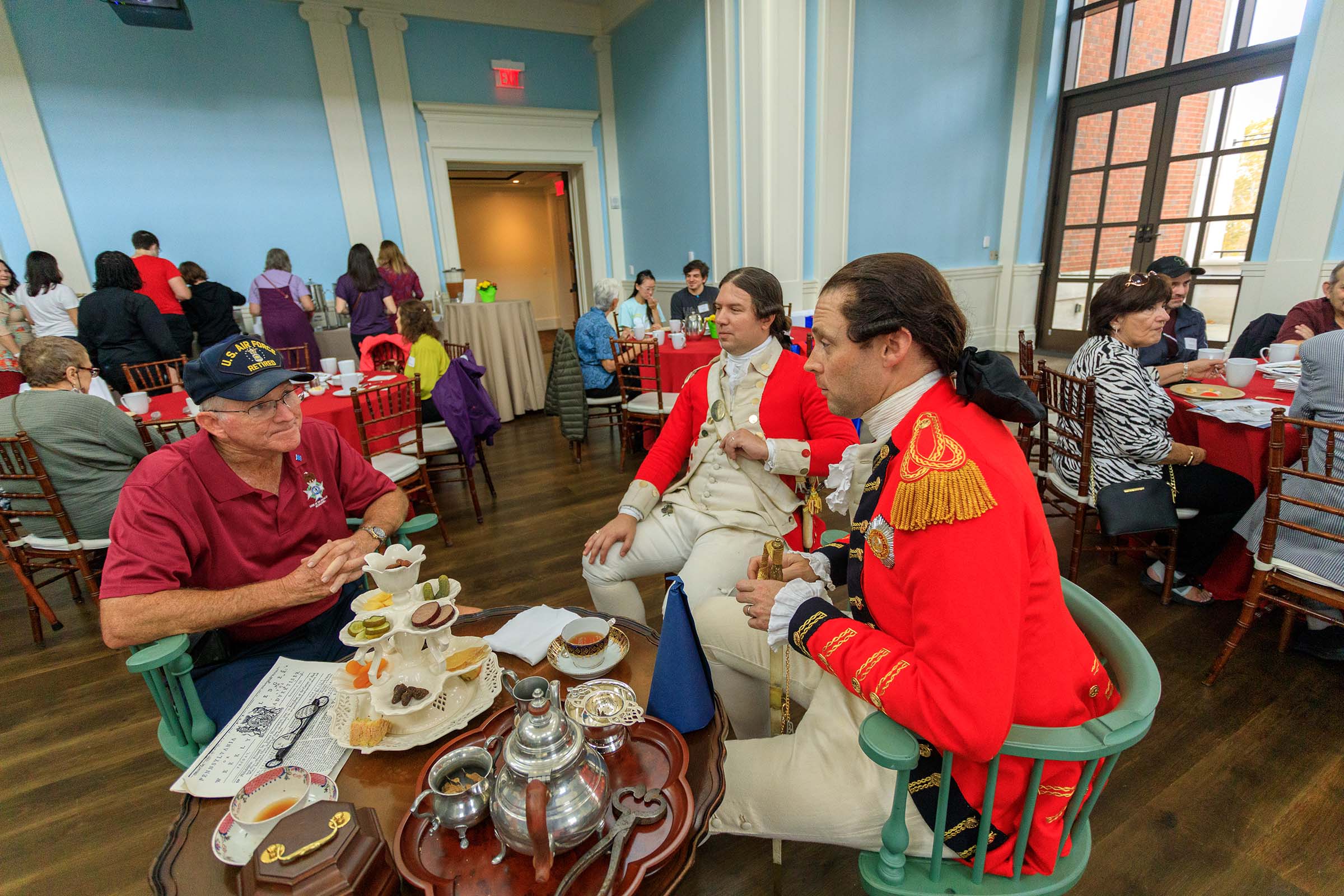 A Museum Member talks to two costumed living historians dressed as British redcoats at the member teatime at Occupied Philadelphia.