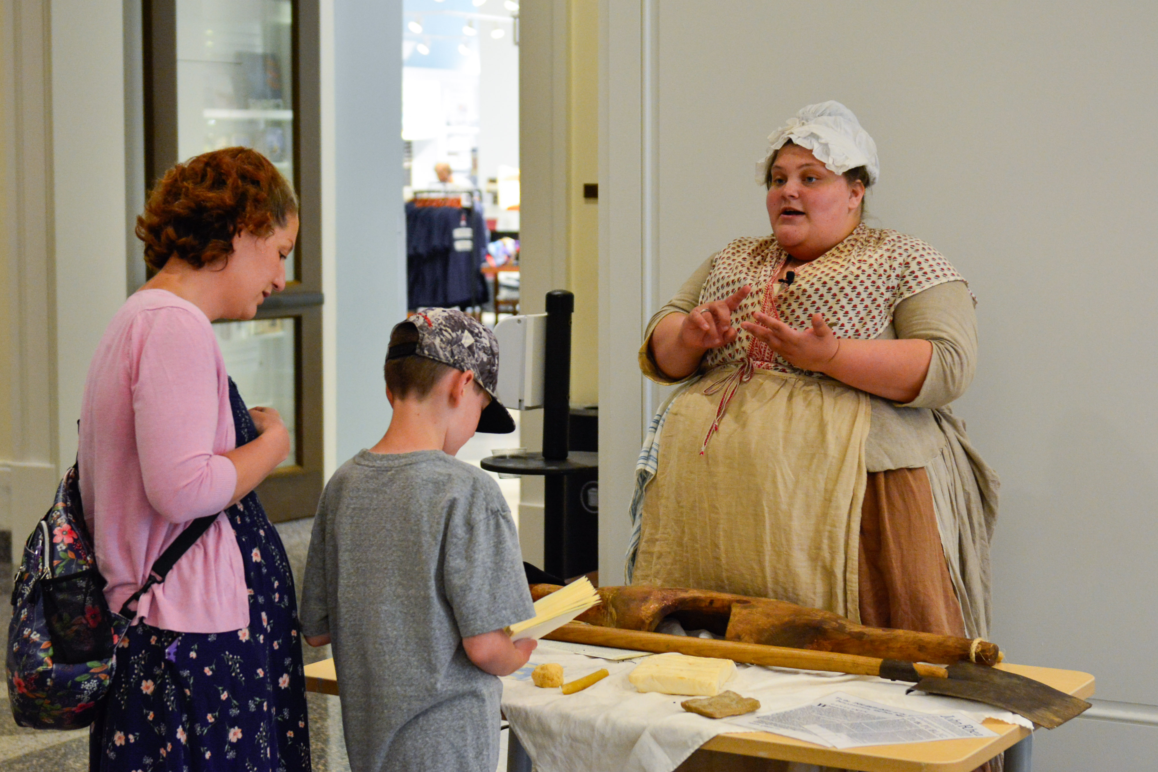 Costumed historical interpreter Sydney Marenburg speaks with a mother and her young son about soap making in the 18th century at the Museum.