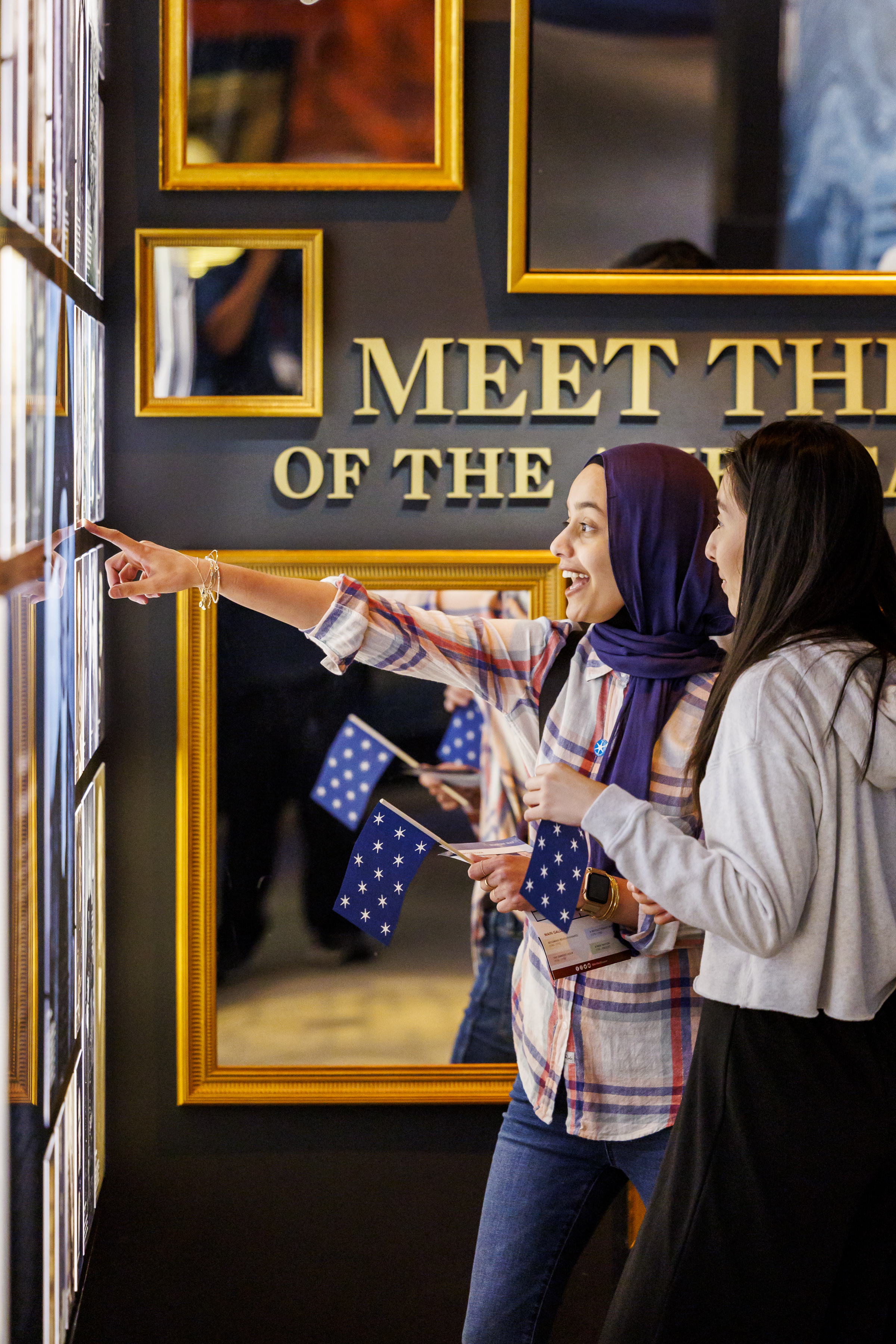 Two visitors point our a historic photo at the Revolutionary Generation wall at the Museum.
