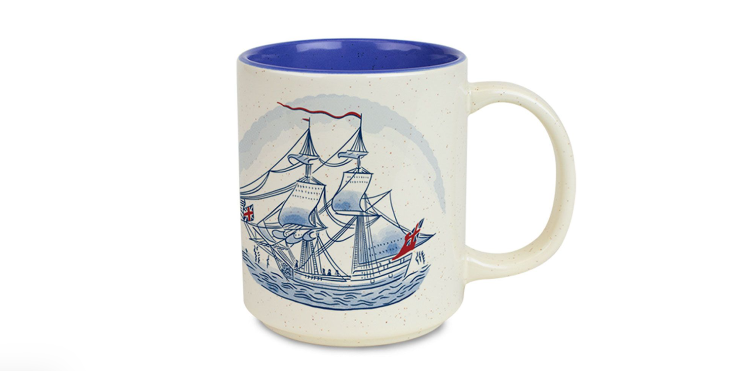 This image features a white mug with a blue painted interior with a blue two-mast tall ship on the outside.