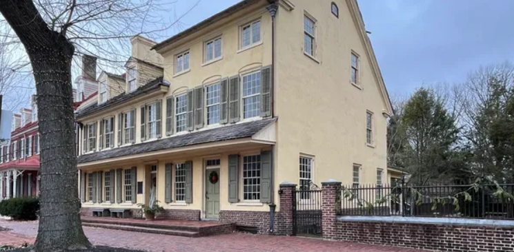 This image shows the exterior beige with olive green shutters building of the Indian King Tavern Museum.