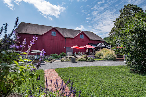 This image shows a large red barn and flowers in the foreground that make up Chaddsford Winery.