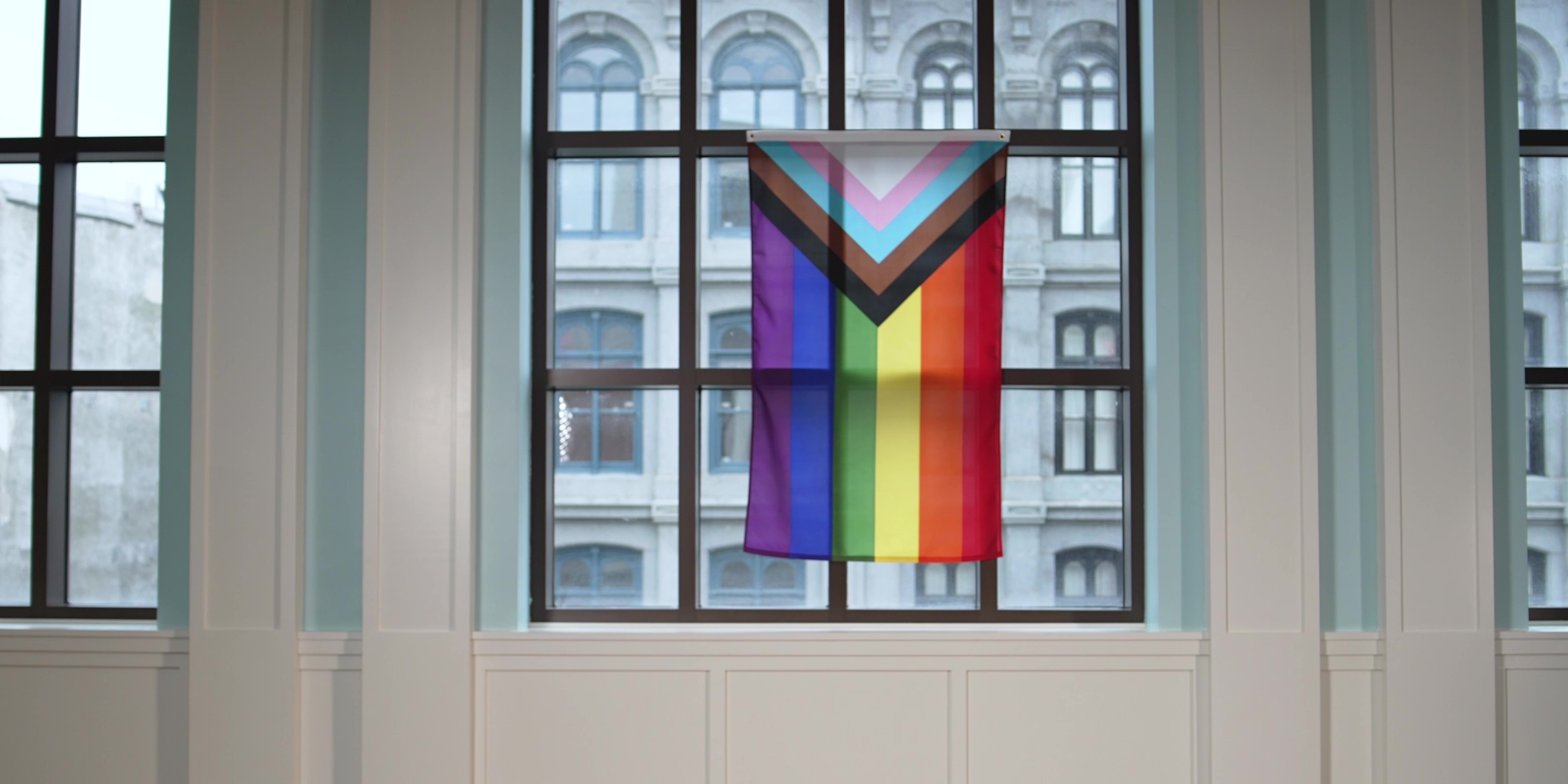 The Pride flag featuring rainbow stripes along with the striped in-cut triangle of white, pink, baby blue, brown, and black for transgender rights of all races hangs from a window in the Museum's Liberty Hall.