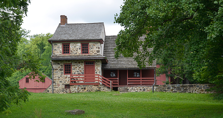 This image shows an old stone home with red doors, shutters, and details at Brandywine Battlefield Park.